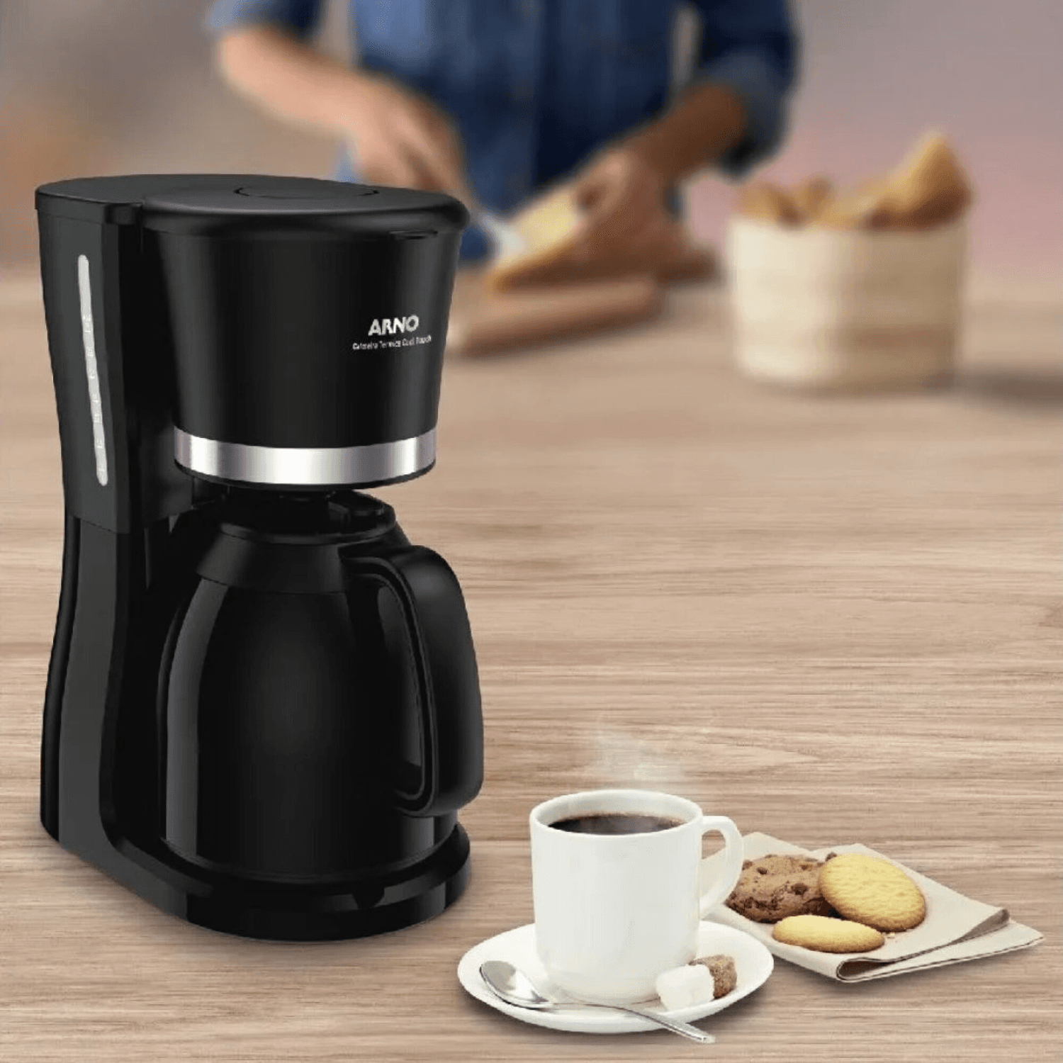Cafetera Arno CM1328B2 con una taza de café y galletas sobre una mesa de madera