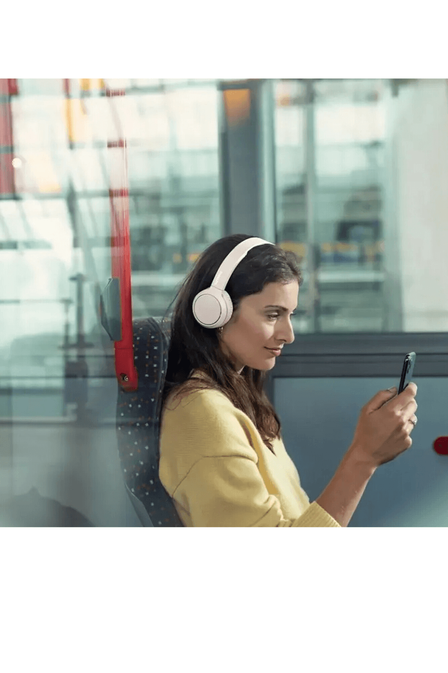Mujer usando auriculares Philips TAH4205WT/00 en el tren