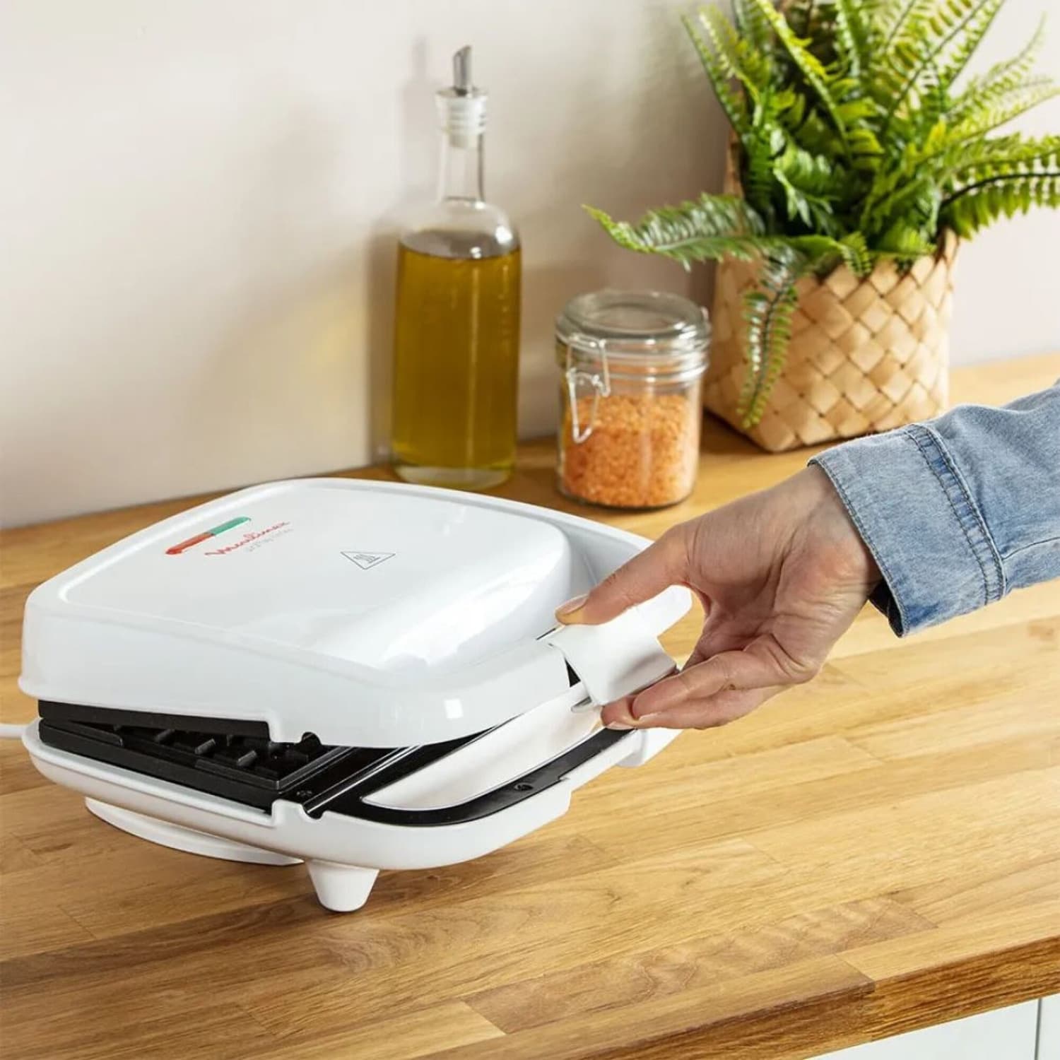 Mano abriendo la wafflera Moulinex WJ170112 sobre una mesada